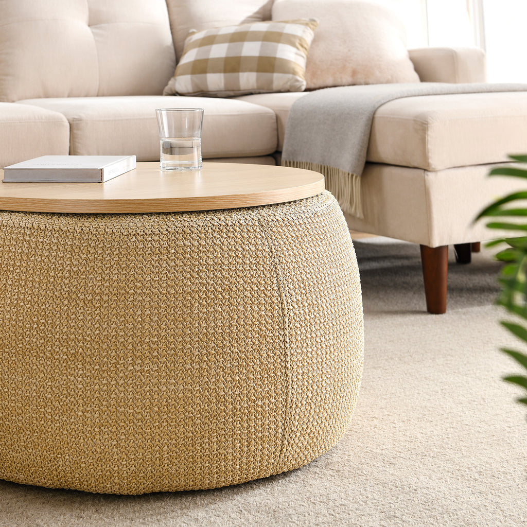 Beige textured ottoman with a glass of water on a wooden surface in a living room setting.