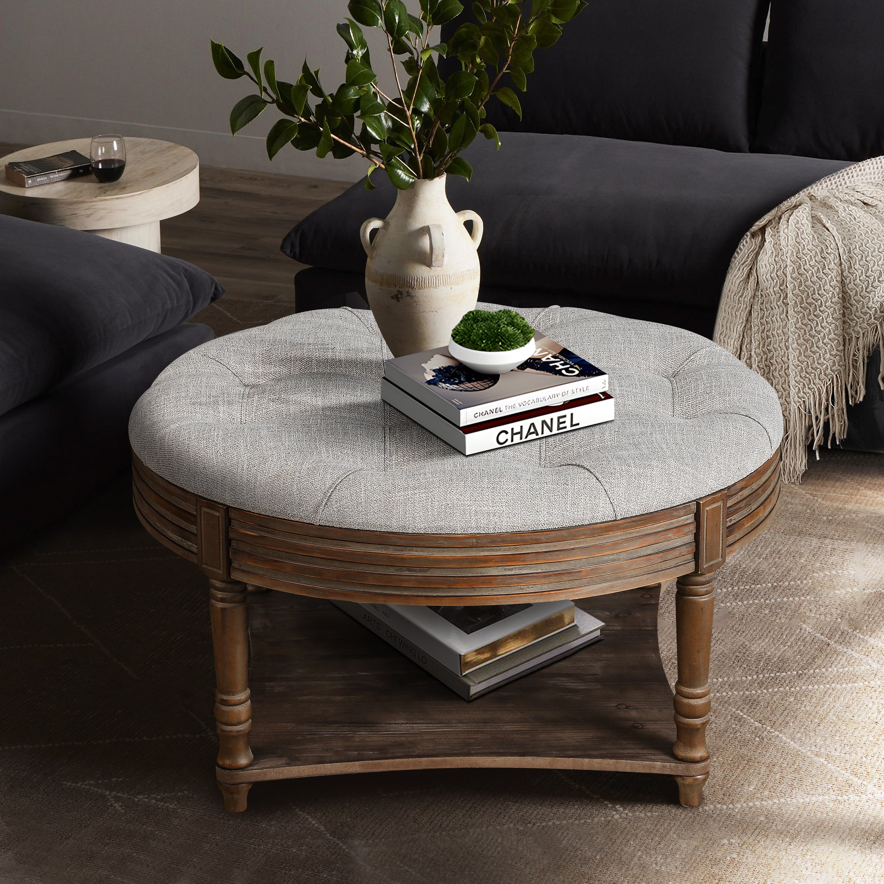 Round light gray upholstered ottoman with wooden frame and storage shelf