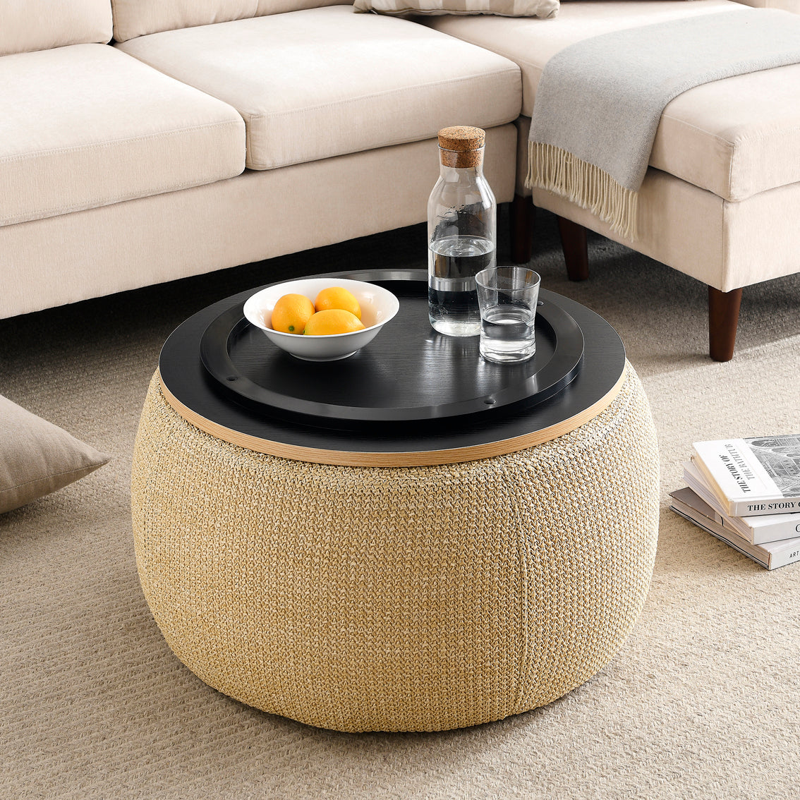 Round woven coffee table with a black top in a living room setting.