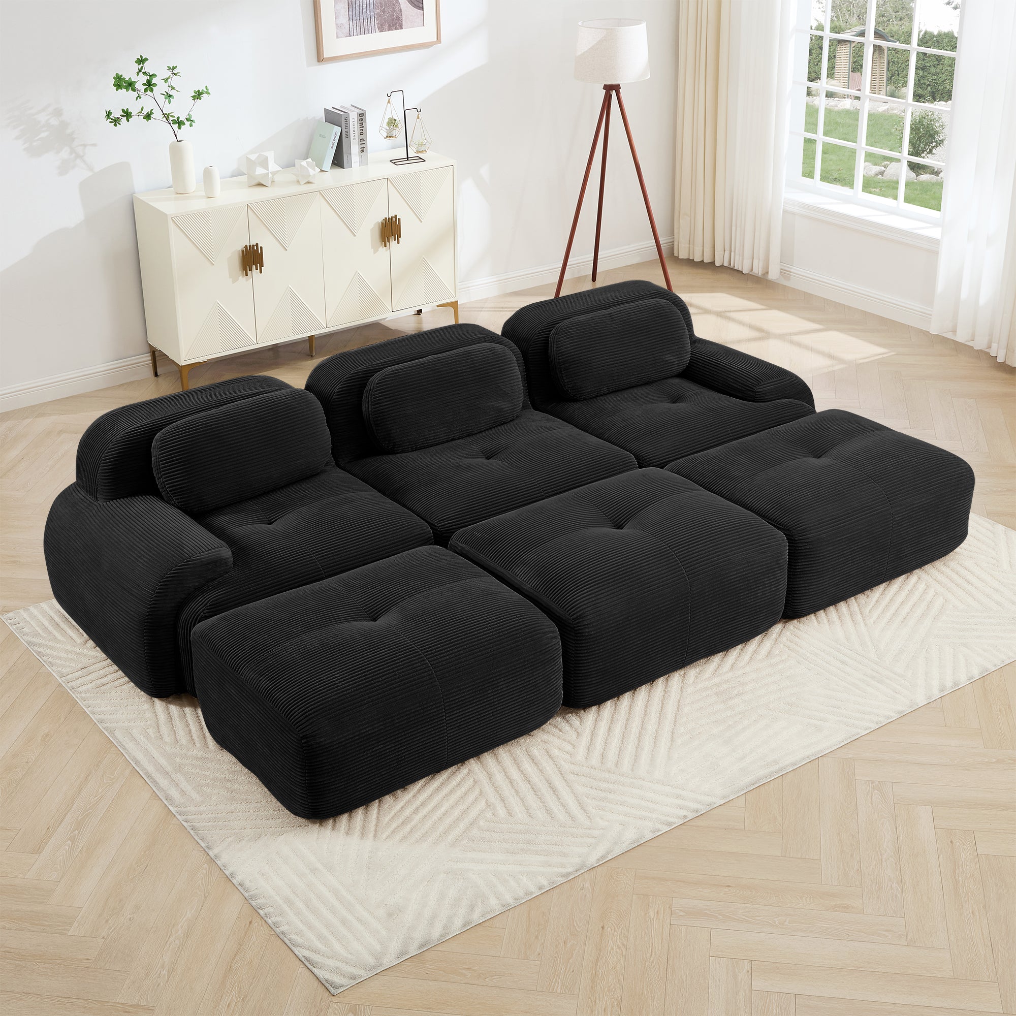 Black sectional sofa in a living room setting with a rug and decor.